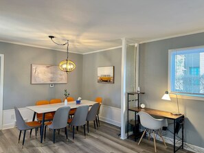A dining area with a table, chairs, a pendant light, artwork on the walls, and a window with blinds. - 3500sf, Arcade, 6bdrm,  2 kitchen, 3baths, Parking (Niagara Falls)
