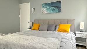 A bedroom with a bed, a nightstand, a lamp, a door, and a painting on the wall. - Arcade, Close to Fall, 4bdrm,  off street Parking (Niagara Falls)