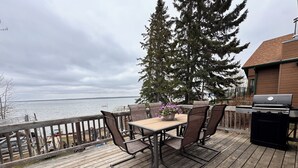 A wooden deck with a table and chairs, overlooking a body of water.