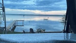 A view of a calm lake with a dock, a chair, and a boat.