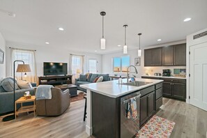 A modern kitchen with a central island, dark cabinetry, and pendant lighting. - The Guss Stop l Gallatin House (Belgrade)