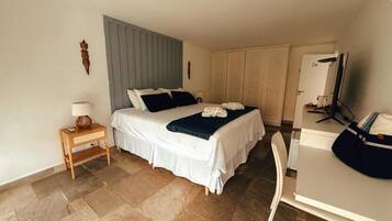 A hotel room with a bed, bedside table, lamp, and a desk with a chair.