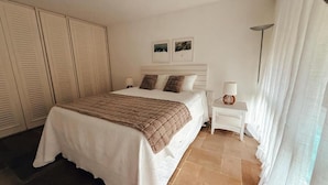 Une chambre d’hôtel avec un lit, des tables de chevet, une lampe et une vue sur l’extérieur.