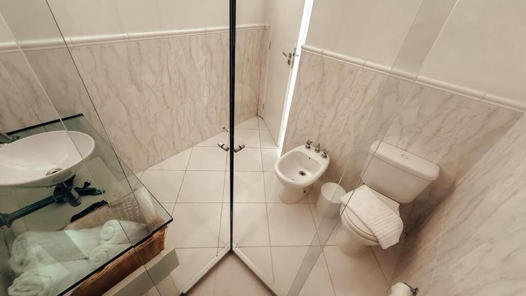 Une salle de bain avec une douche à parois de verre, un lavabo, un bidet et des toilettes.