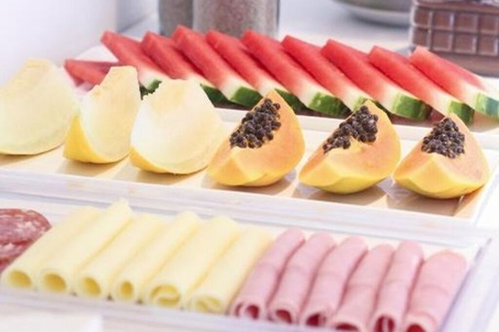 A selection of sliced fruits and deli items, including watermelon, papaya, and various cheeses and meats.