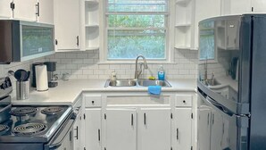 Une cuisine moderne avec des armoires blanches, un évier en acier inoxydable et un four encastré.