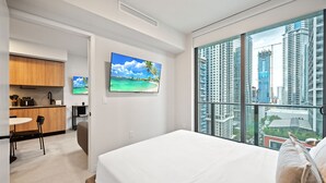 A modern hotel room with a large bed, a dining area, a kitchen, and a city view. - Luxury 1BR+Den 2BA Rooftop Pool Miami (Miami)