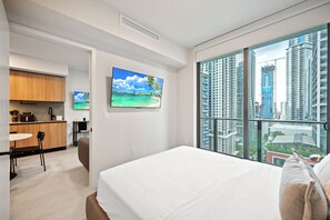Ein modernes Hotelzimmer mit einem großen Bett, einem Essbereich, einer Küche und Blick auf die Stadt.