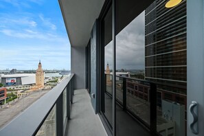 Ein Balkon mit Blick auf eine Stadtlandschaft, darunter ein markanter Turm und moderne Gebäude.