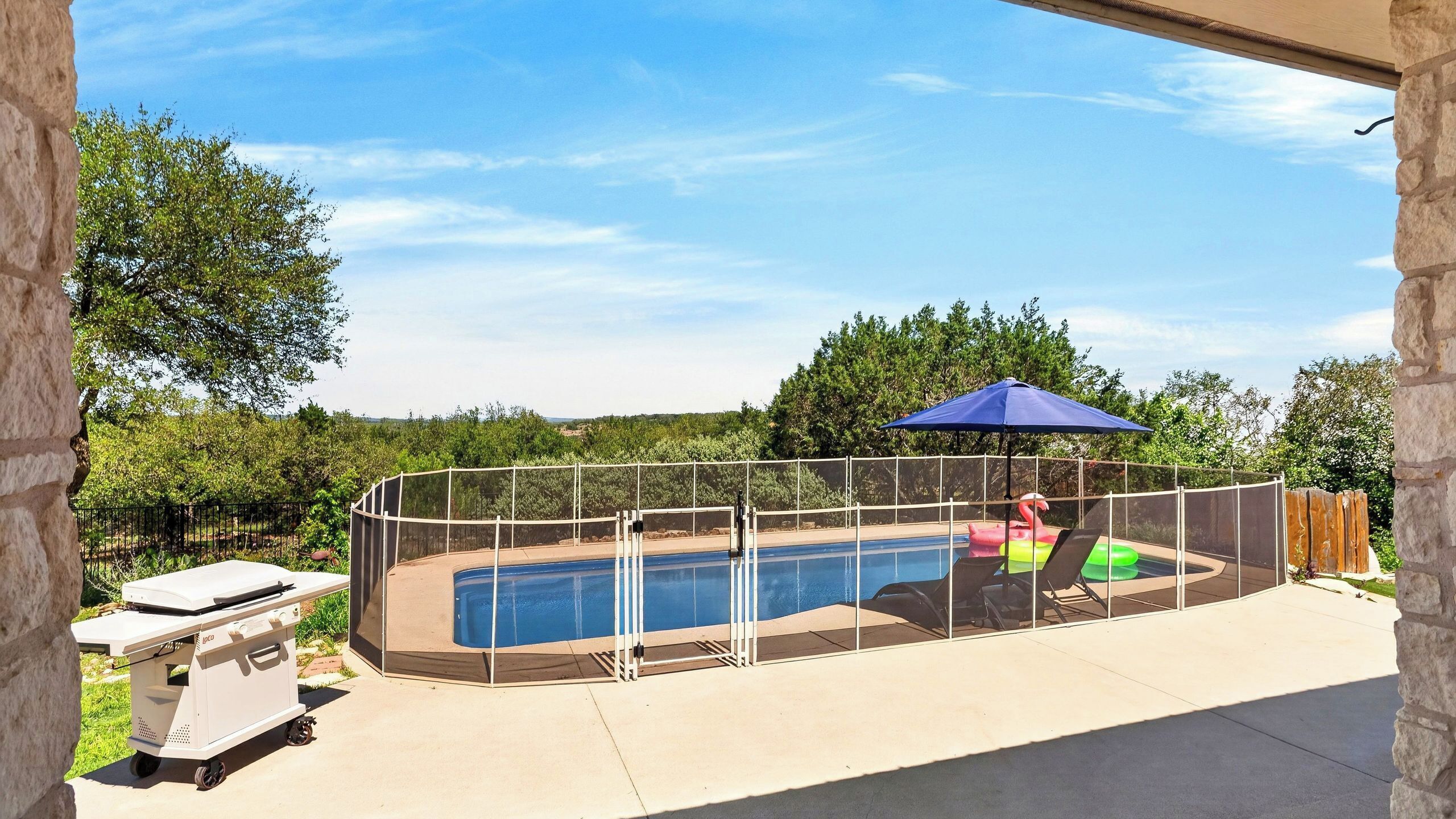 Un patio trasero con piscina, una parrilla y un porche cubierto.
