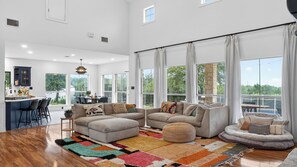 A spacious living area with a large sofa set, a dining table, and a kitchen area with bar stools. - Bonham Retreat by Avantstay Non-toxic Wellness Home + Recording & Podcast Studios + Infrared Sauna Pool + Firepit Hill Country (Dripping Springs)