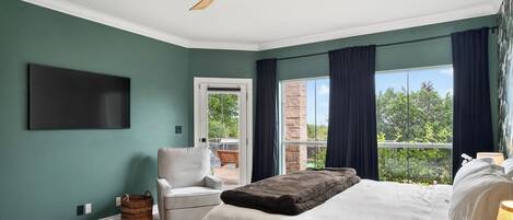 Ein Schlafzimmer mit Bett, Sessel, Deckenventilator, Fernseher und Blick ins Freie.