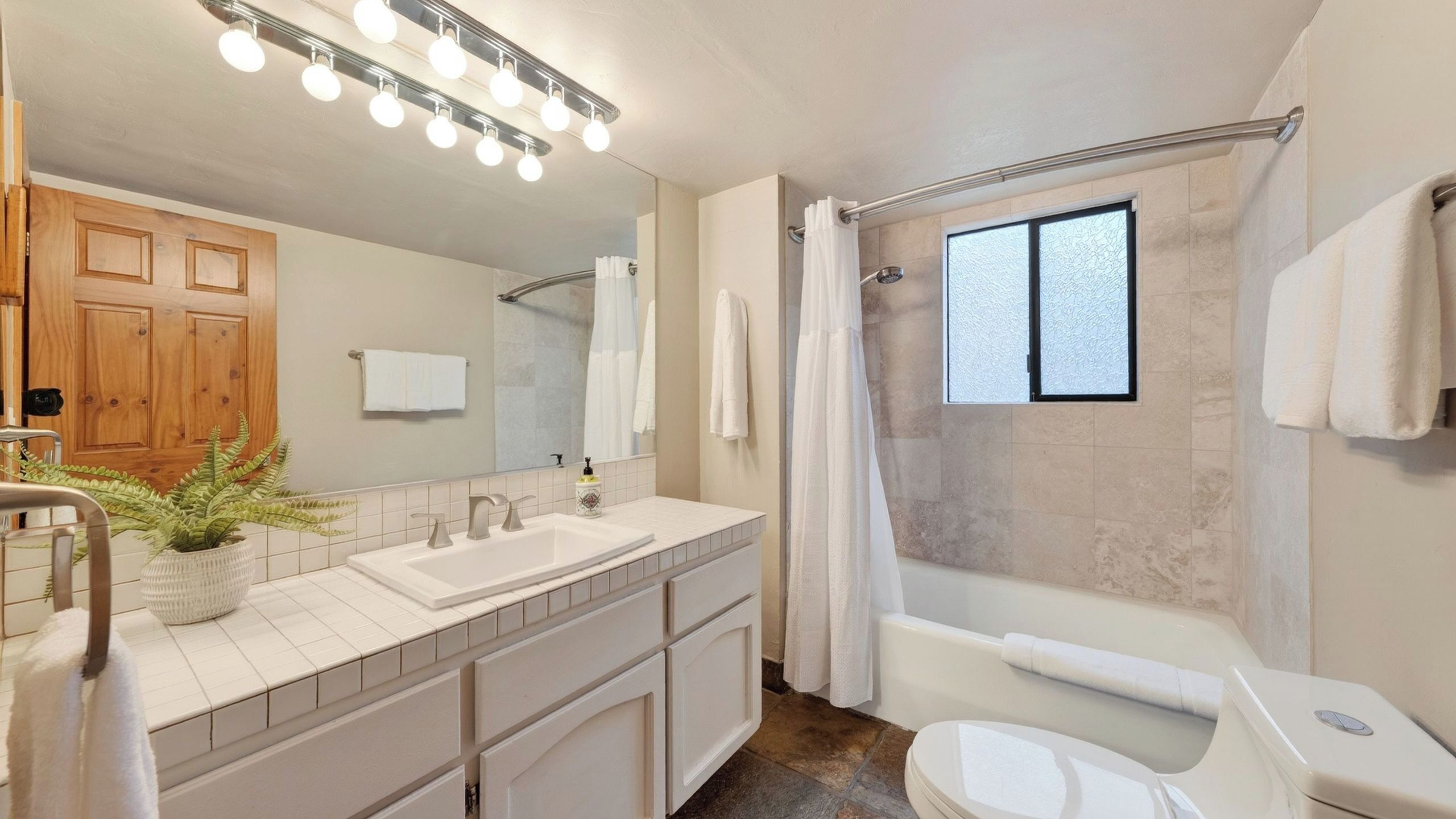 Une salle de bain avec un meuble-lavabo à deux vasques, un grand miroir, une douche avec une porte en verre et une fenêtre.
