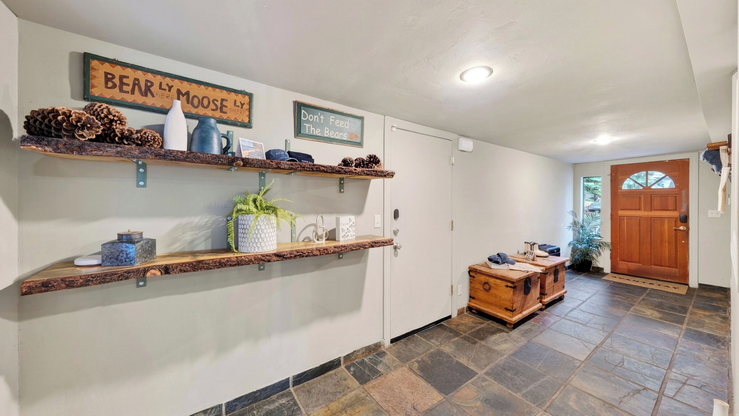 A hallway with wooden shelves, a door, and a stone-tiled floor.