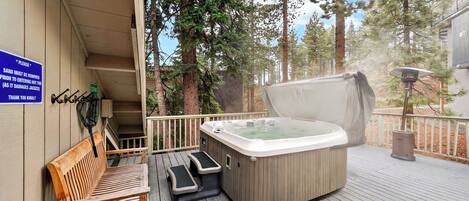 A hot tub on a wooden deck with a bench and a sign about sand removal.