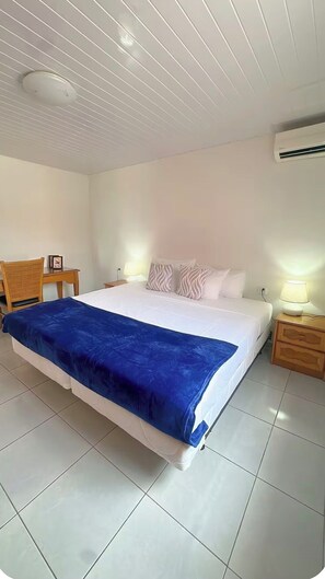 Une chambre d’hôtel avec un lit, des tables de chevet, un bureau et une chaise.
