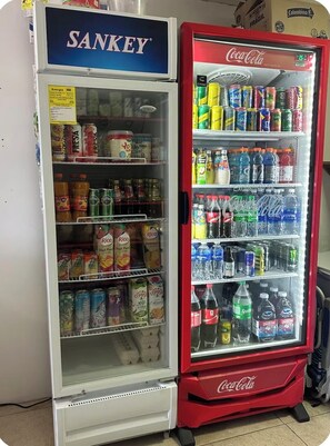 Un distributeur automatique proposant une variété de boissons, notamment des sodas, des jus de fruits et de l’eau.
