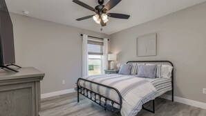 A bedroom with a bed, a ceiling fan, a window with curtains, a bedside table, and a wall-mounted lamp. - ‼️Citrus Springs 3BR - Gulf & Springs 30 Min (Citrus Springs)