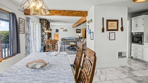 A dining area with a table, chairs, and a chandelier. There is a kitchen area with cabinets and appliances. - Terra Alta Lake View - Pool, Game Room (Terra Alta)