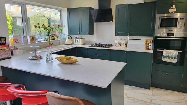 Una cocina moderna con una isla central, armarios oscuros y un ventanal grande.