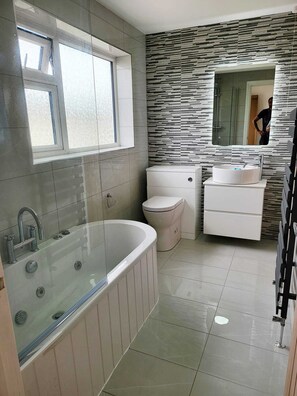 A modern bathroom with a bathtub, toilet, and sink.