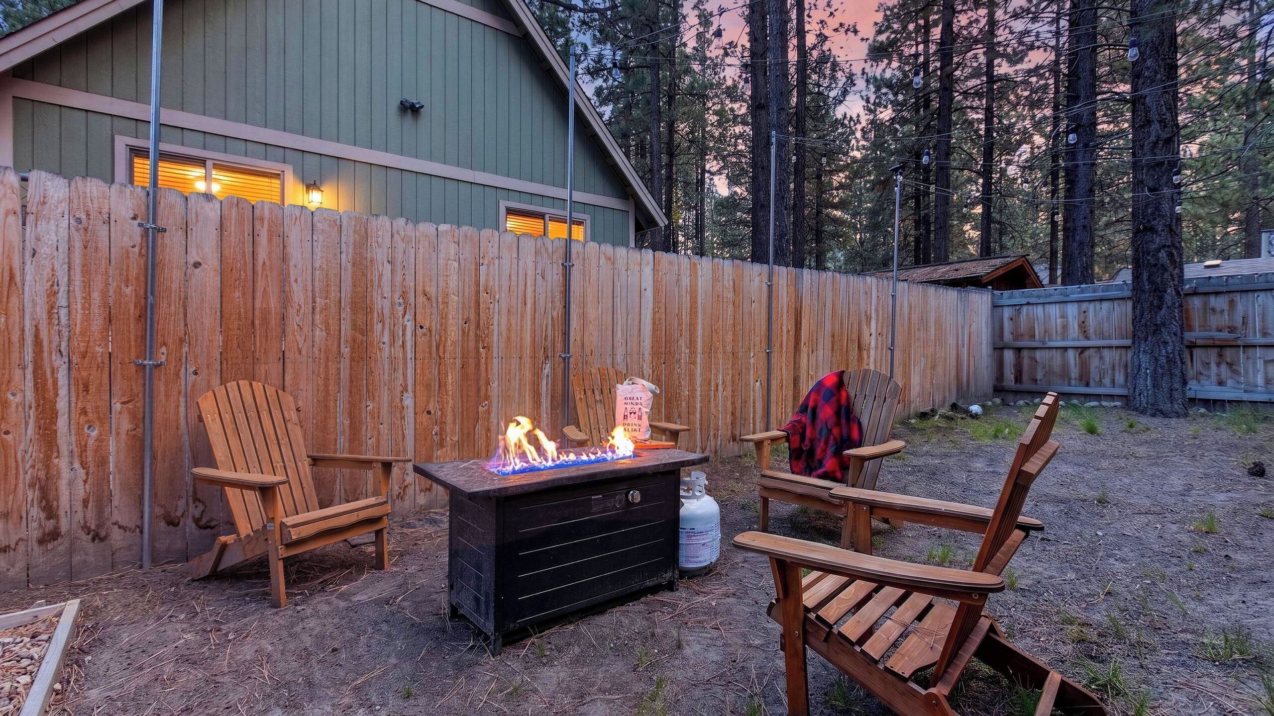Ein Garten mit Holzzaun, Feuerstelle und zwei Holzstühlen.