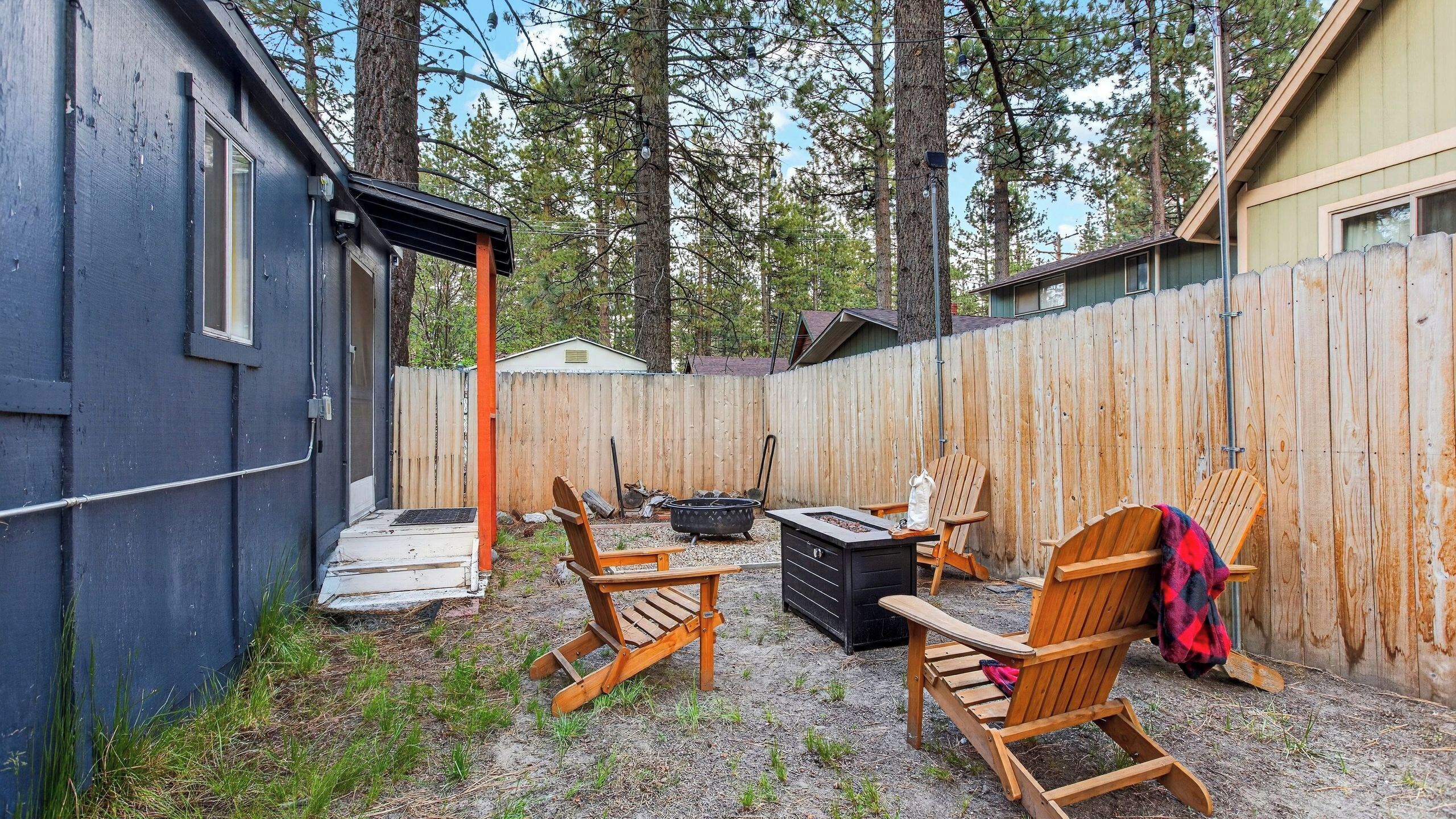 Un jardin avec une terrasse en bois, un espace salon extérieur, un foyer et un abri de jardin.