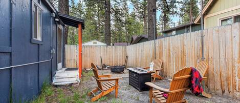 A backyard with a wooden deck, outdoor seating, a fire pit, and a shed.