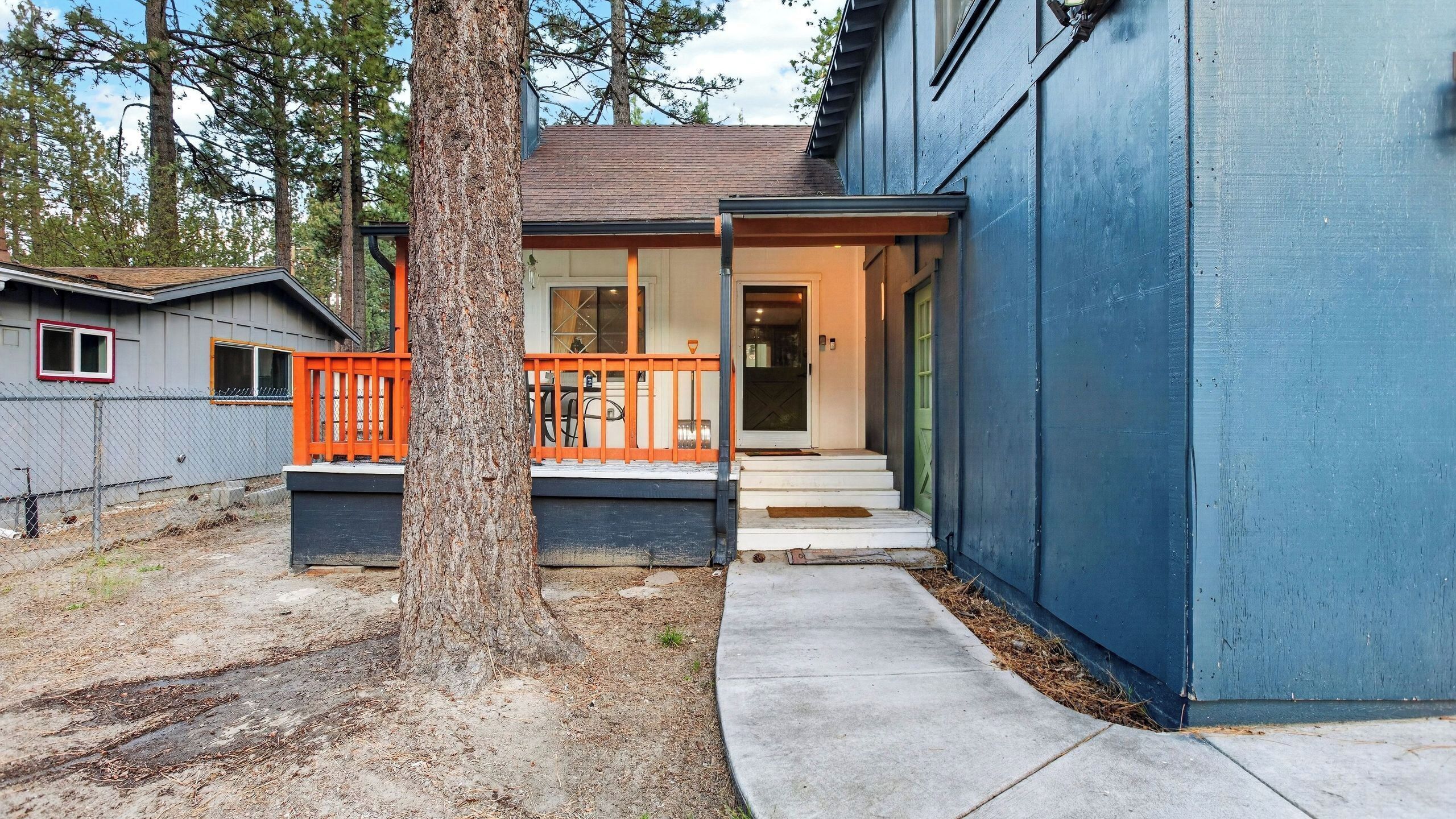 A residential building with a porch, a visible door, and a fenced yard.