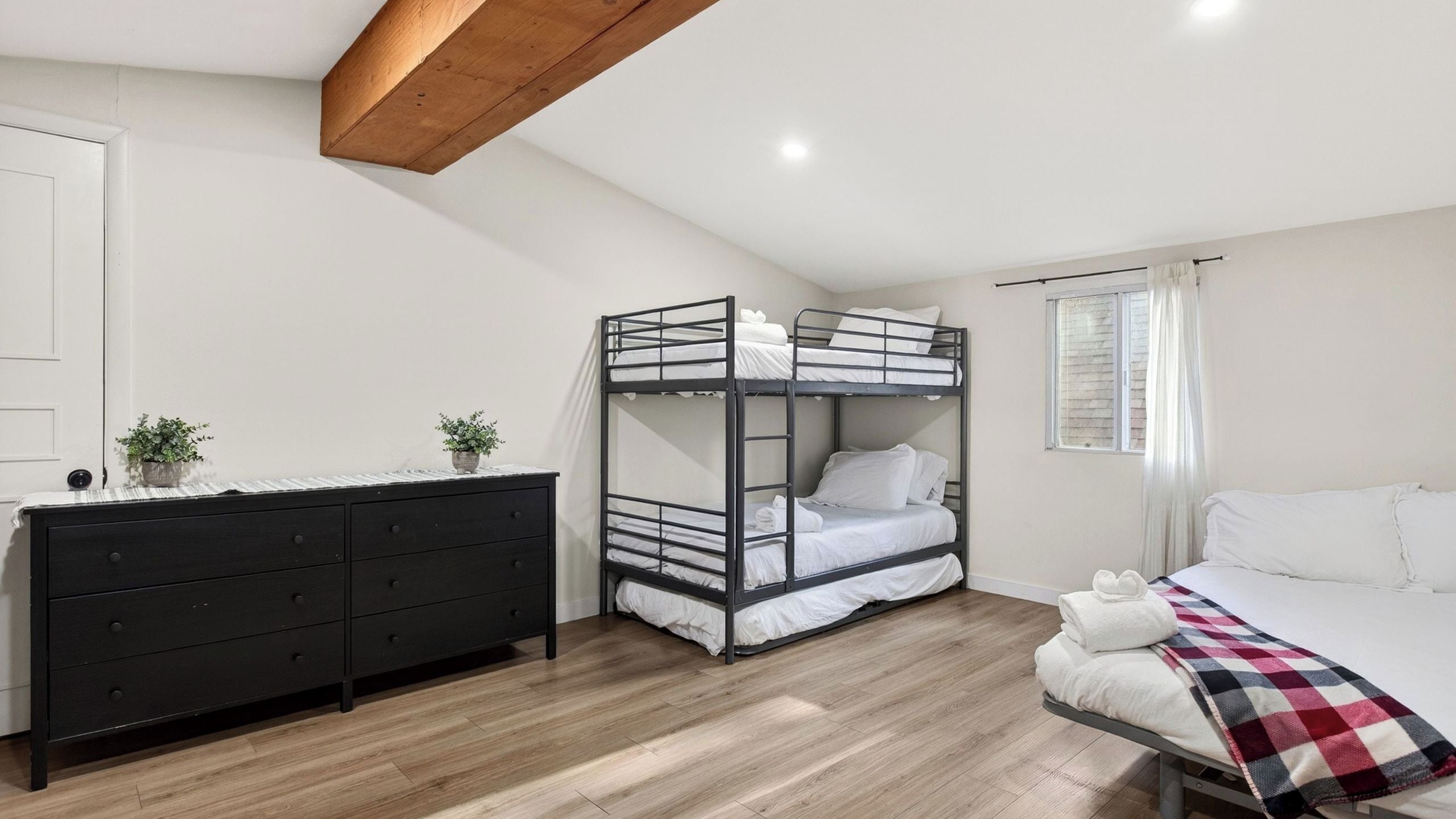 Une chambre avec un lit superposé, une commode et une fenêtre.