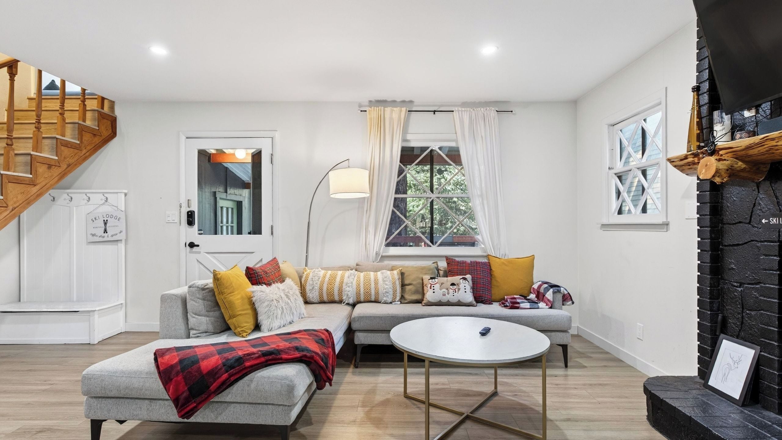 Una sala de estar con sofá, mesa de centro, chimenea y escalera.