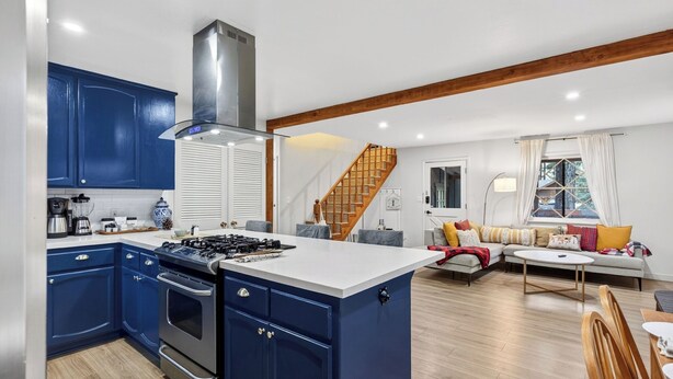 A modern kitchen with blue cabinets, a central island, and a stove.