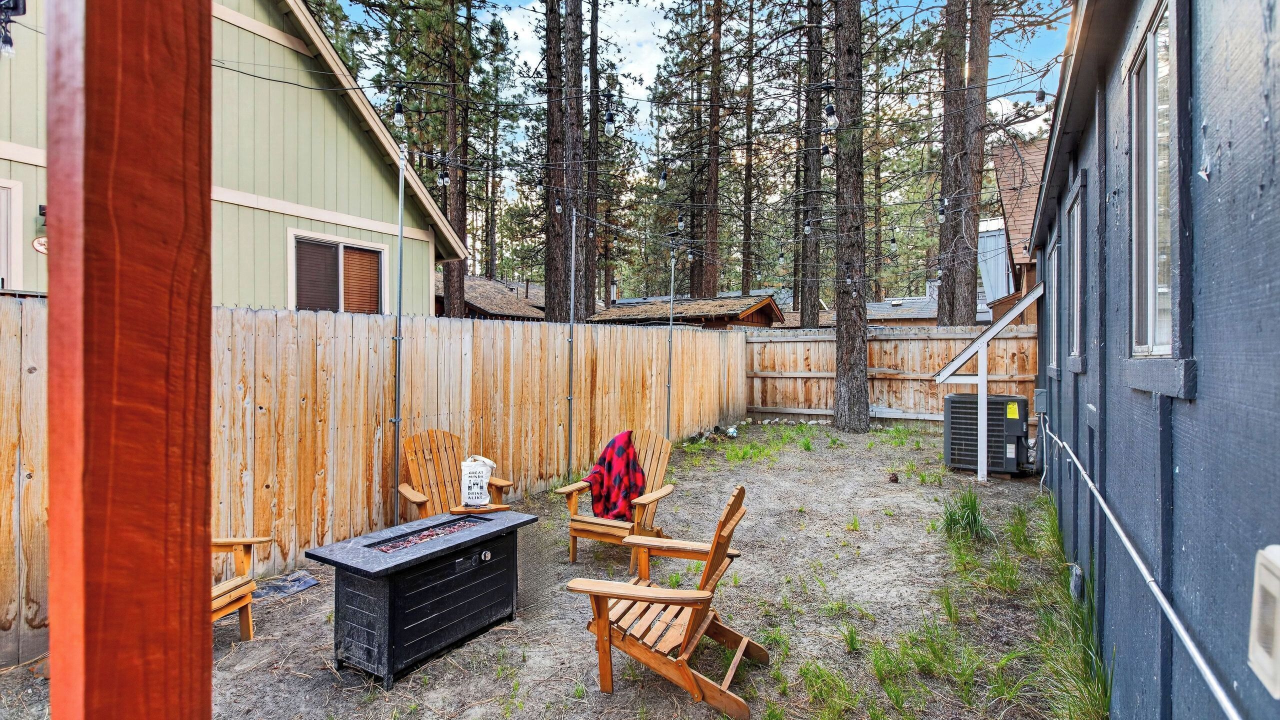 A backyard with a wooden deck, a grill, and outdoor seating.