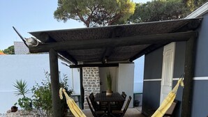 Um pátio com uma rede, uma mesa com cadeiras e um muro de pedra.