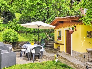 Eine Terrasse mit Tisch und Stühlen, ein gelbes Gebäude und ein Garten.