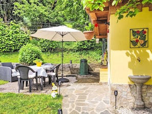 Eine Terrasse im Freien mit Tisch und Stühlen, einem hängenden Blumentopf und einer dekorativen Gartenzwerg.