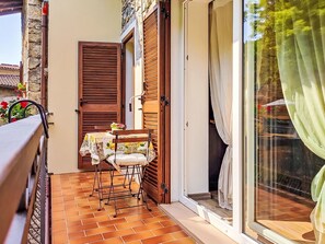 A patio with a table and chairs, a wooden door, and a sliding glass door. - La Casetta di Lulù by Interhome (Osteno)