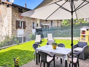 Eine Terrasse mit Tisch und Stühlen, einem gelben Topf und einer kleinen Hund-Figur.