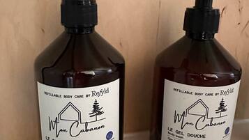 Deux flacons de produits de soins pour le corps rechargeables de la marque Refillable, posés sur une étagère.