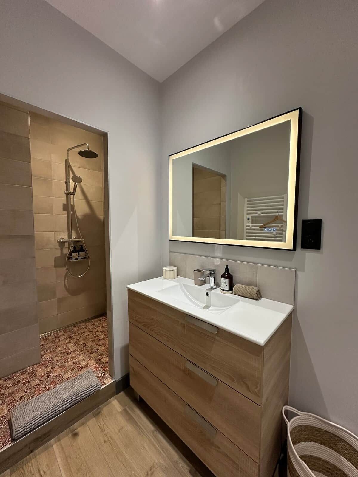 A modern bathroom with a shower, vanity, and a large mirror.