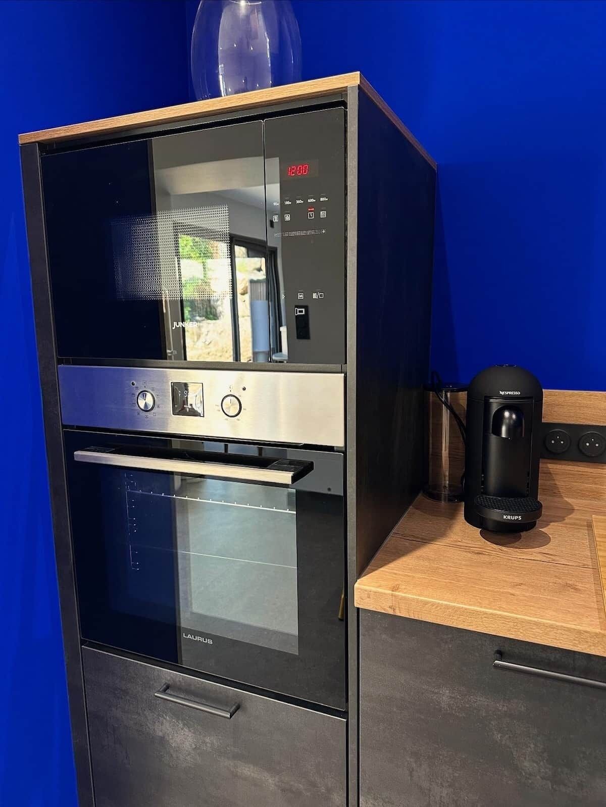 A modern kitchen with a built-in oven, a coffee maker, and a window with a view.