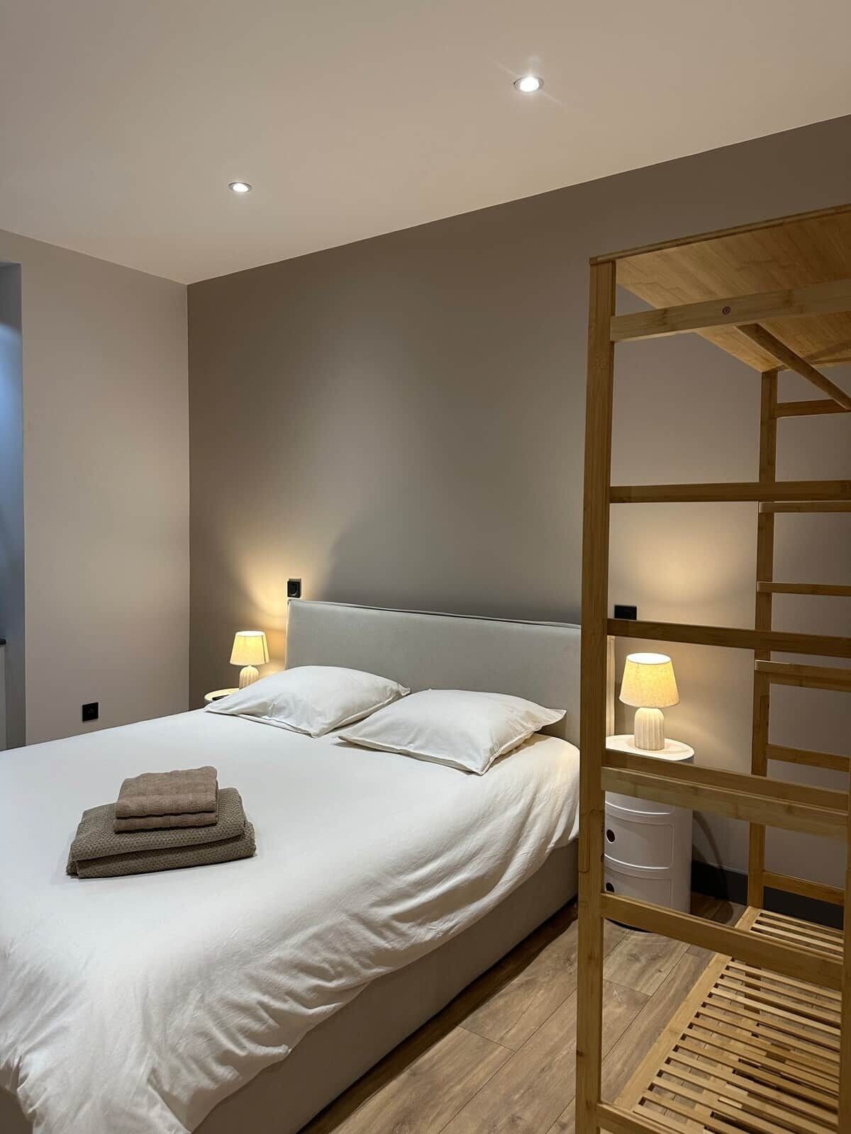 Um quarto moderno com uma cama, duas luminárias de cabeceira, uma estante de madeira e uma luz no teto.