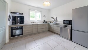 A modern kitchen with stainless steel appliances, a large window, and a pendant light. - Le Christophe - Jardin - BBQ (Saint-Christophe)