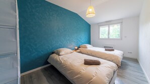 A bedroom with two beds, a window, and a hanging light fixture. - Le Christophe - Jardin - BBQ (Saint-Christophe)