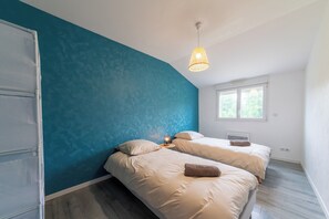 Ein Schlafzimmer mit zwei Betten, einem Fenster und einer Pendelleuchte.