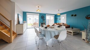 A dining area with a table set for four, a sofa, a coffee table, and a staircase. - Le Christophe - Jardin - BBQ (Saint-Christophe)