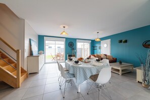 Ein Essbereich mit Tisch für vier Personen, einer Couch, einem Couchtisch und einer Treppe.
