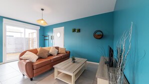 A living room with a brown sofa, a white coffee table, and a blue wall. - Le Christophe - Jardin - BBQ (Saint-Christophe)