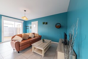 Ein Wohnzimmer mit einem braunen Sofa, einem weißen Couchtisch und einer blauen Wand.