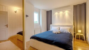 Quarto com cama, mesa de cabeceira, janela e porta.